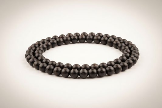 Create a premium studio-quality product image of a **Karungali Mala 6mm** made from natural ebony wood black beads. Arrange the mala neatly in a full circular or flowing shape so the entire mala is clearly visible. Use a clean white or soft cream background with soft shadows for a luxury look. Make the 6mm beads appear smooth, polished, and authentic with a subtle spiritual aura, highlighting protection, meditation, and Hindu spiritual energy. Keep the style minimal, elegant, and

