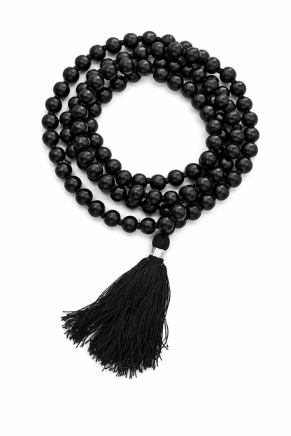 Dhivarashi black beaded mala necklace arranged in a coiled pattern with smooth round beads and black tassel on white background