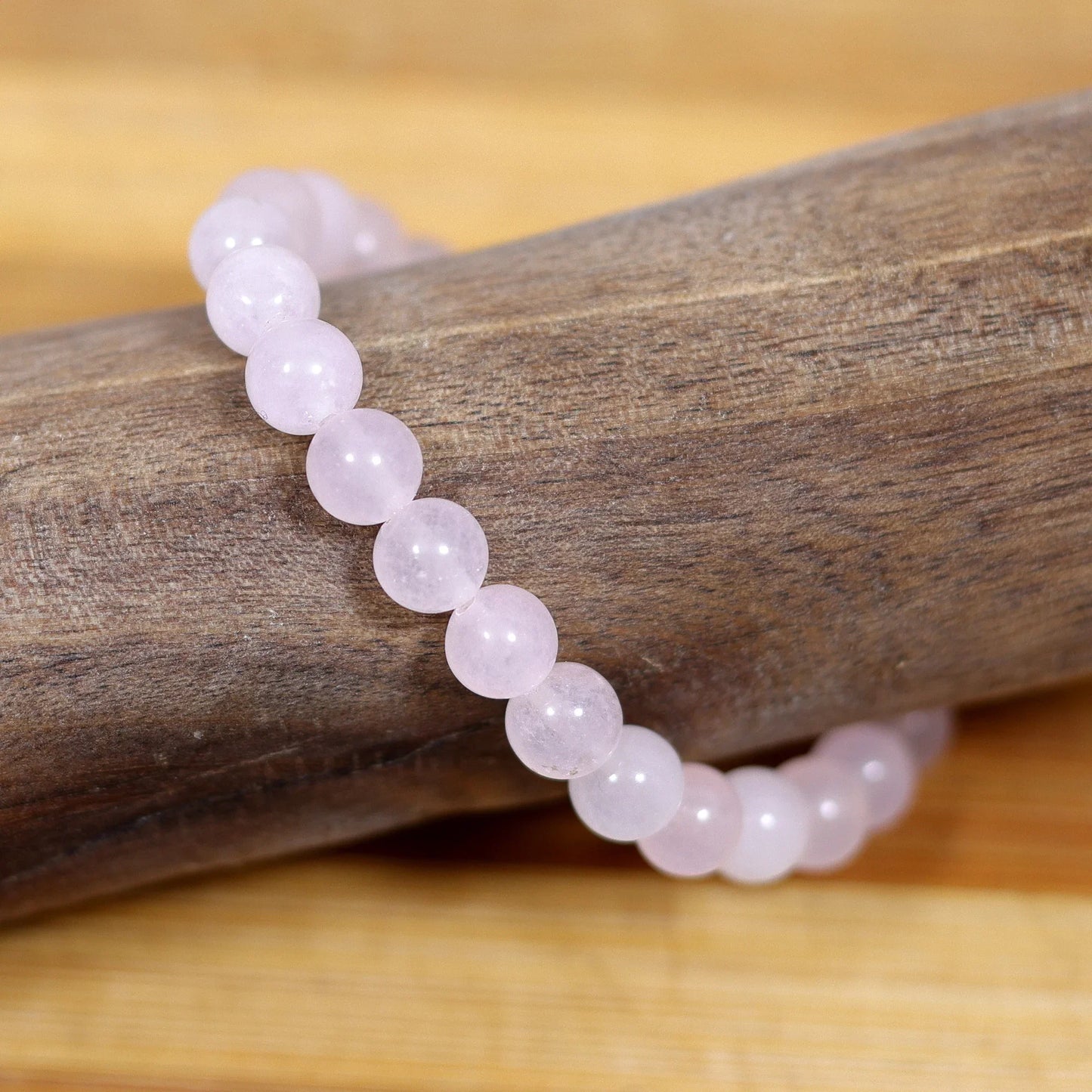 DHIVARASHI rose quartz love bracelet showing natural stone texture, pink gemstone beads on wooden surface highlighting authentic crystal quality